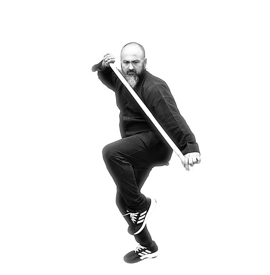 A man with a beard is holding a stick in a black and white photo.