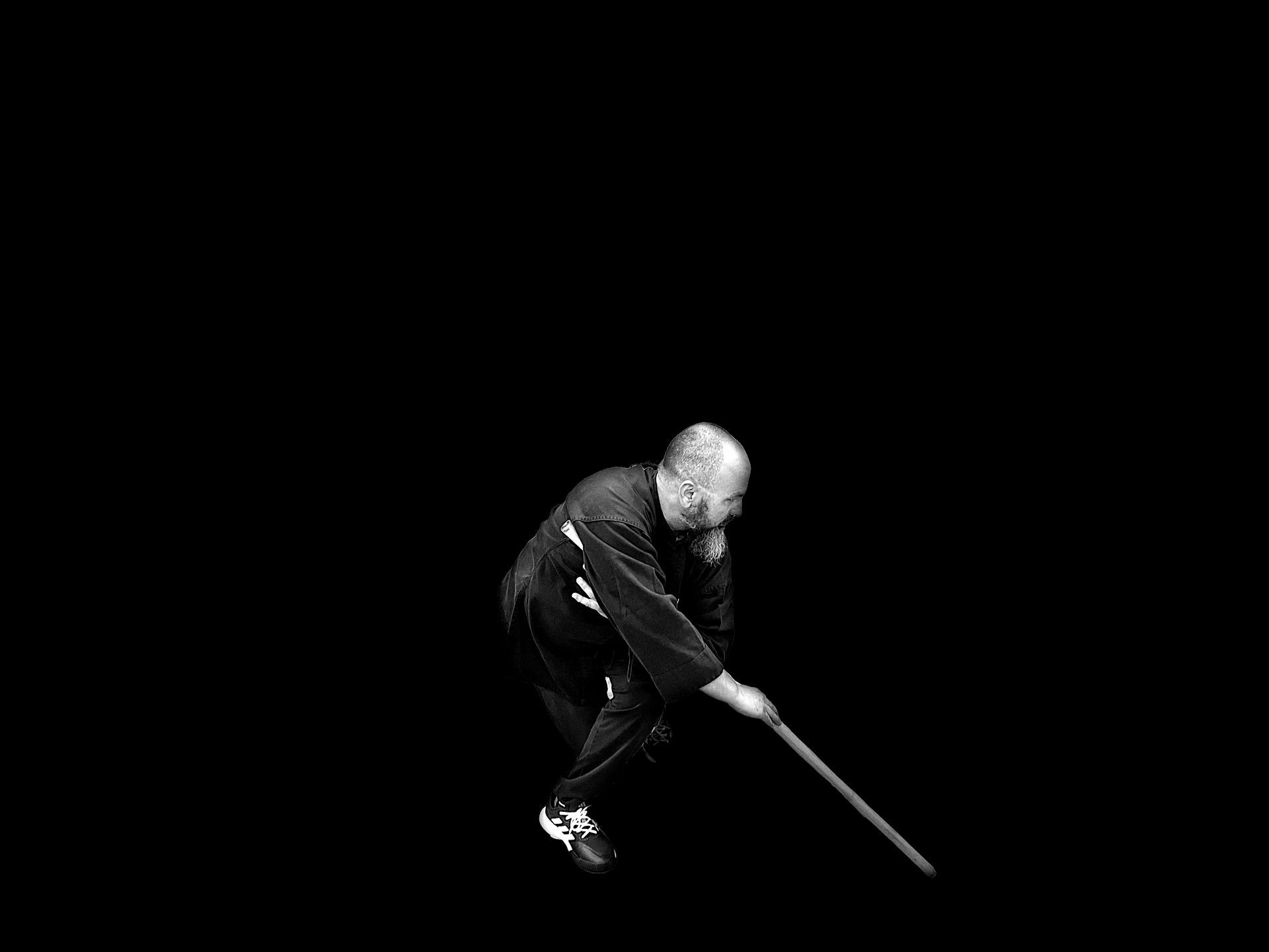 A man is holding a stick in his hand in a black and white photo.