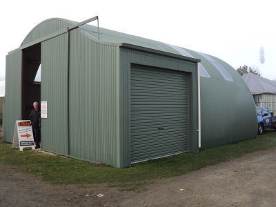A man is standing in front of a large green building