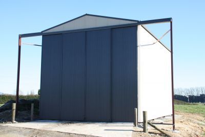 A black and white building with sliding doors is sitting in the middle of a field.