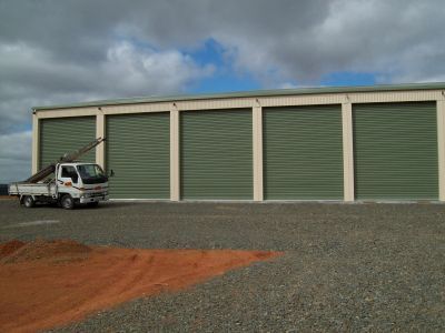 A white truck is parked in front of a building with green doors