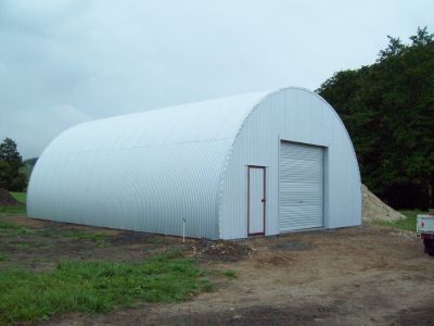 A large white building is sitting in the middle of a field.