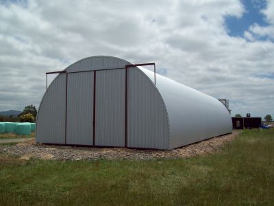 A large white building is sitting in the middle of a grassy field.