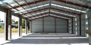 A large empty metal building with a roof and a lot of windows.