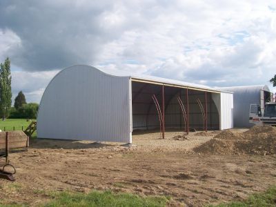 A large white building is sitting in the middle of a dirt field.