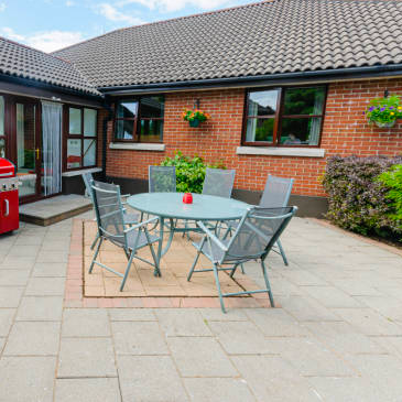 A patio with a table and chairs in front of a brick house.