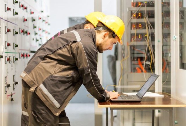 Two Men in Hard Hats Are Working on A Laptop Computer — Lismore Computer Solutions In Lismore, NSW