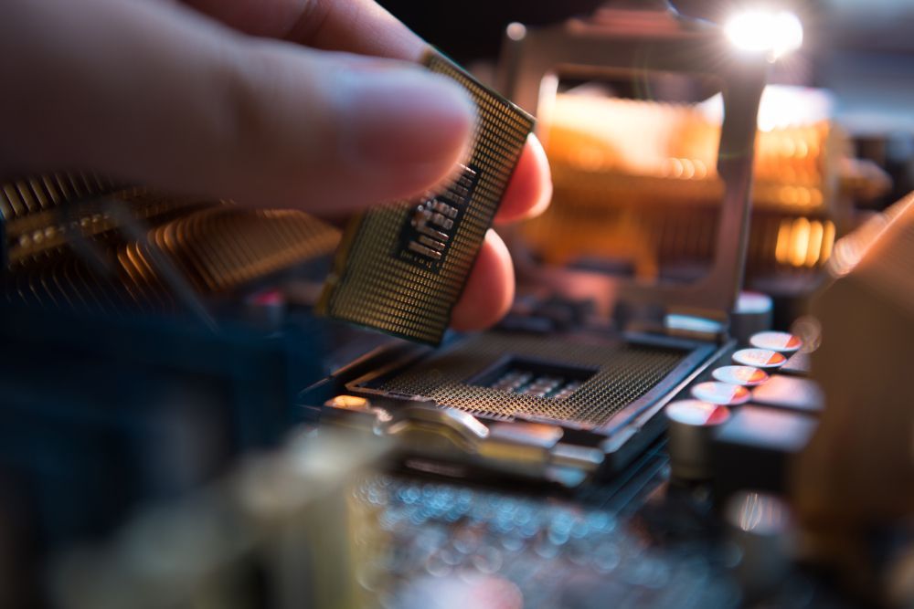 A Person is Holding a CPU in Their Hand in Front of a Motherboard — Lismore Computer Solutions in Alstonville, NSW