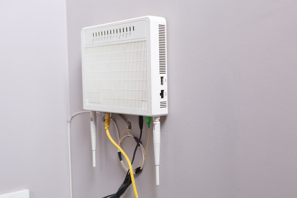 A White Router Is Hanging On A Wall With Wires Coming Out Of It — Lismore Computer Solutions In Lismore, NSW