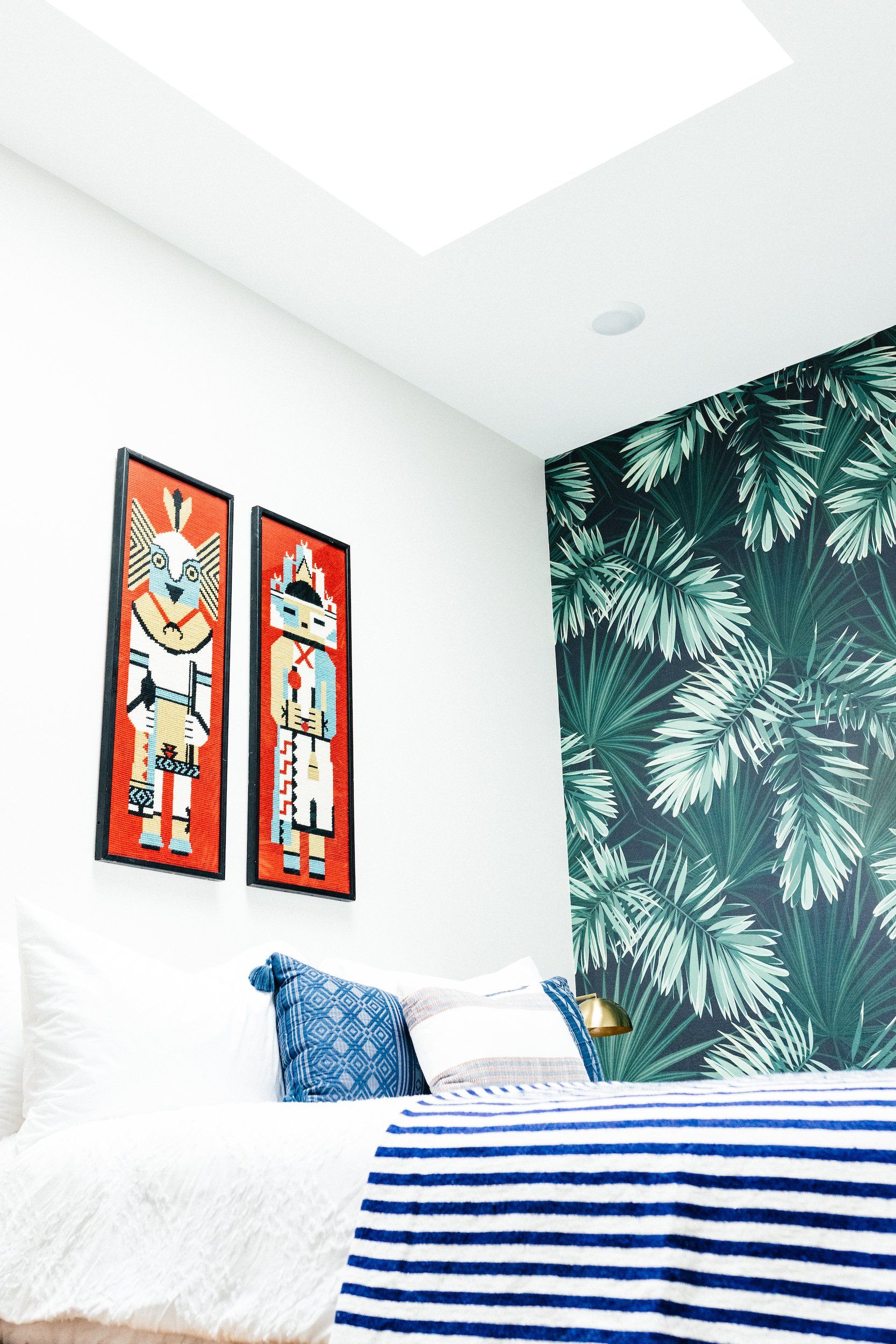 A bedroom with a bed , two paintings on the wall and a skylight.