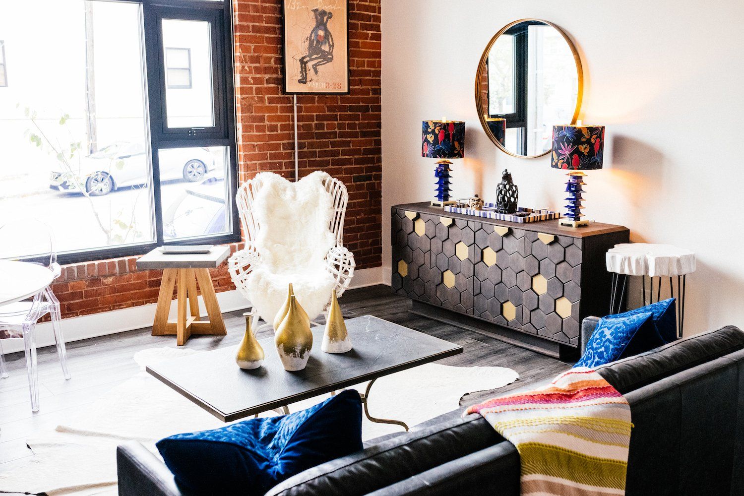 A living room with a couch , chair , coffee table and mirror.