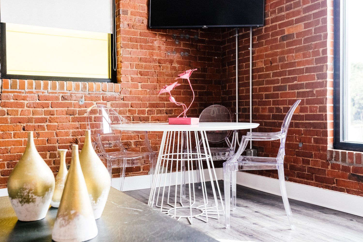 There is a table and chairs in the room with a brick wall.