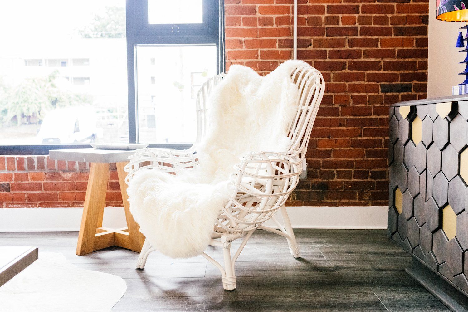 A white chair is sitting in a living room next to a brick wall.