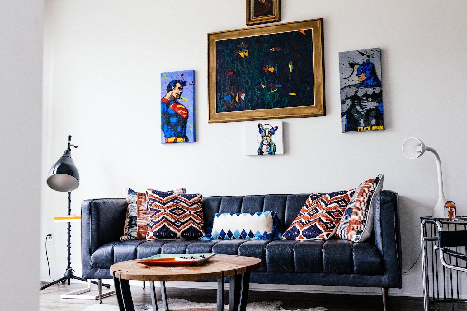 A living room with a couch , table , and paintings on the wall.