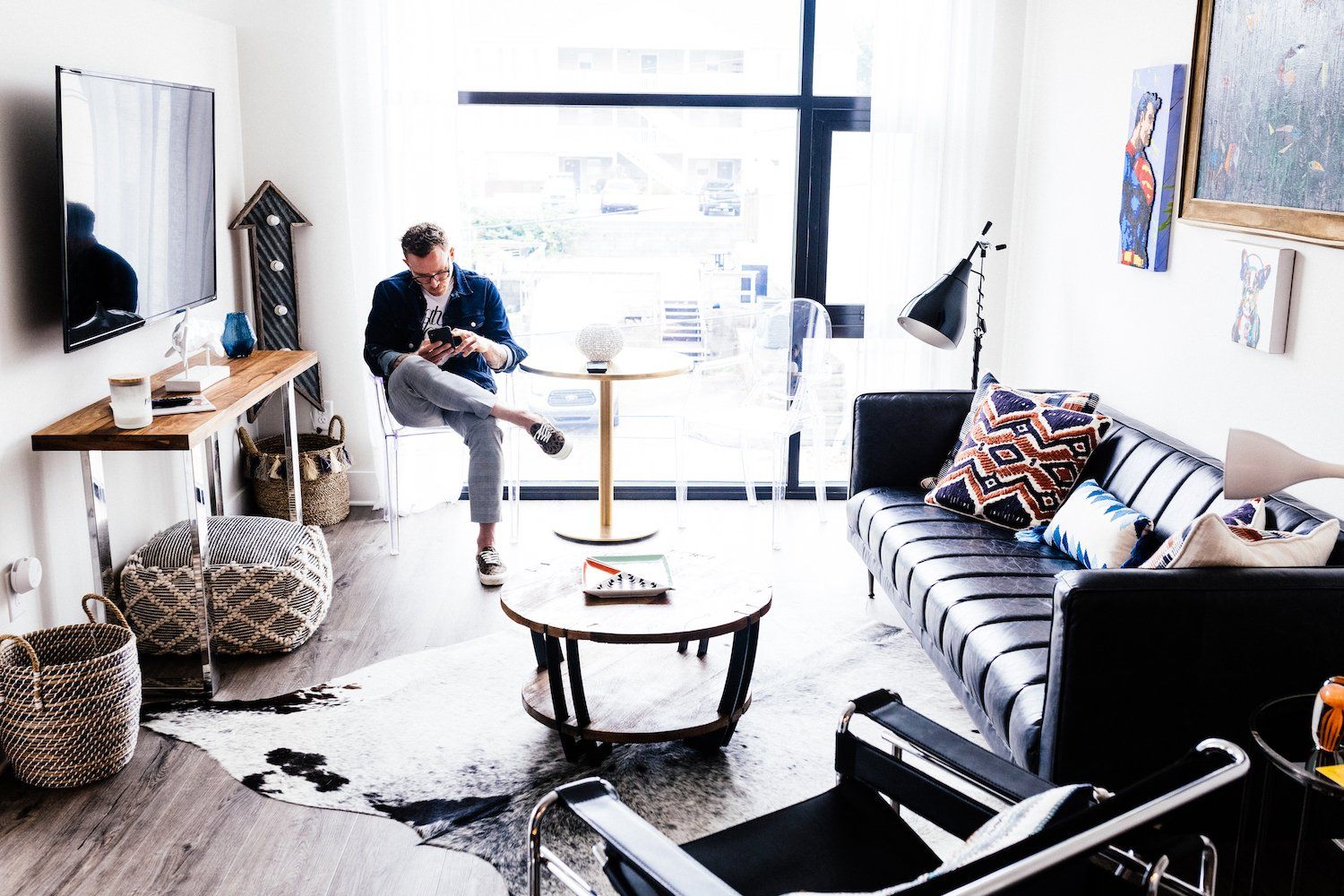 A man is sitting on a chair in a living room looking at his phone.