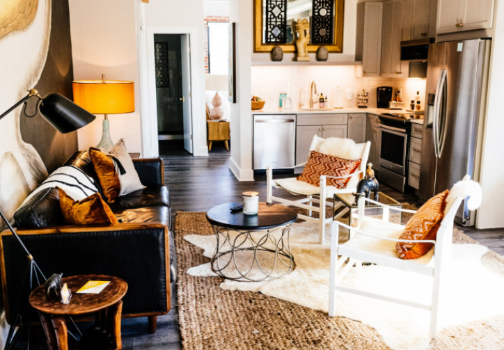 A living room with a couch , chair , coffee table and rug.