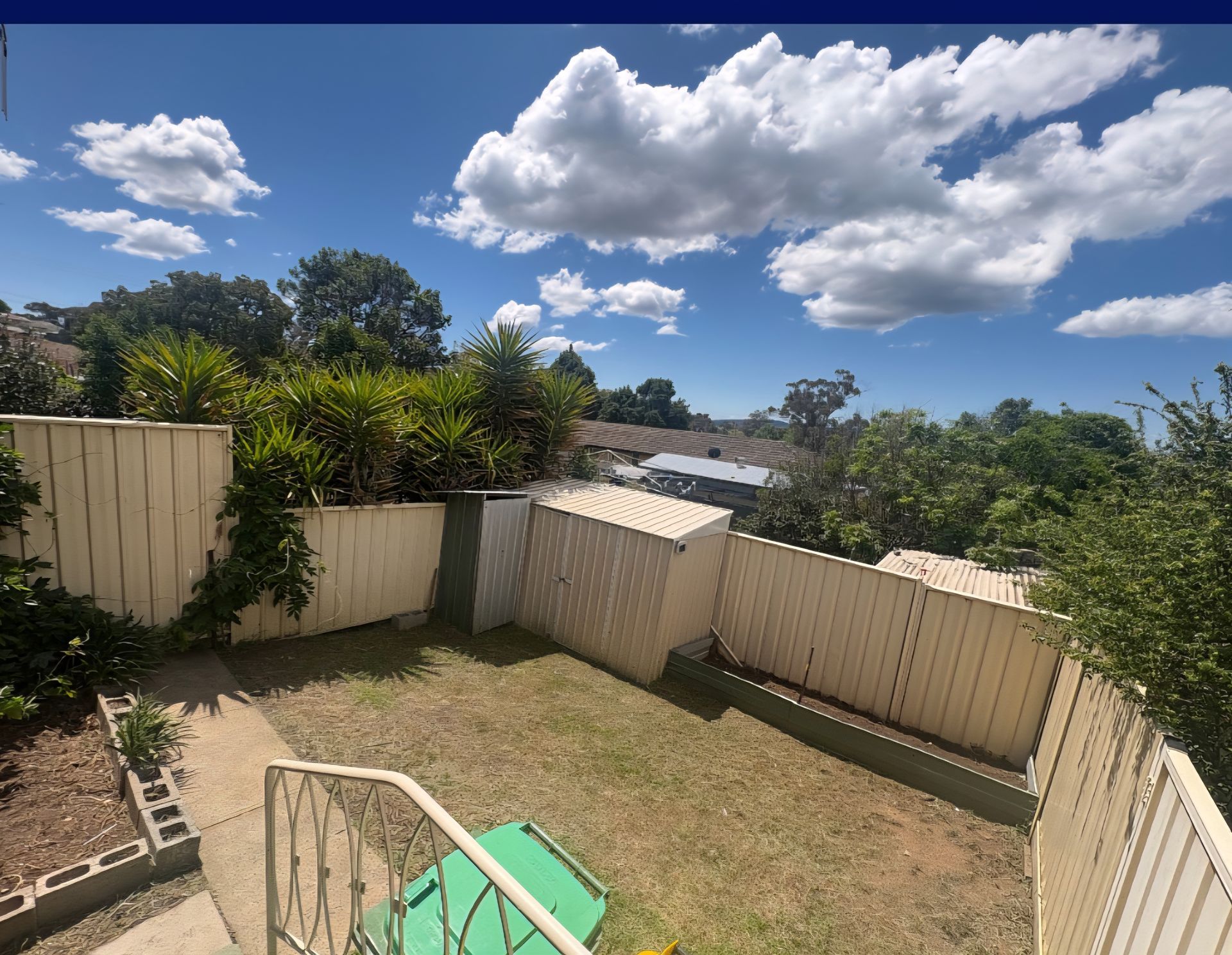 Backyard with A Grassy Area, Bordered by A Beige Fence — Carro's Property Maintenance in Fyshwick, ACT