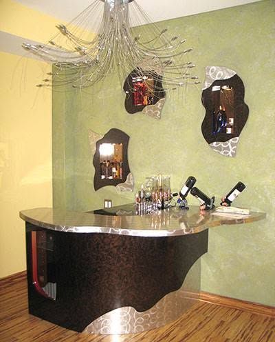 A bar with bottles of wine on it and a chandelier hanging from the ceiling.