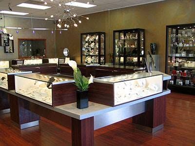A jewelry store with a lot of display cases and a flower on the counter.
