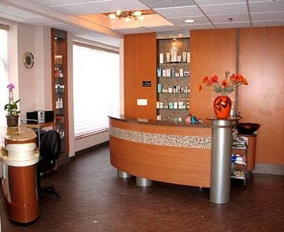 A reception area with a curved wooden counter and a vase of flowers