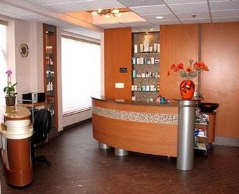 A reception area with a curved wooden counter and a vase of flowers