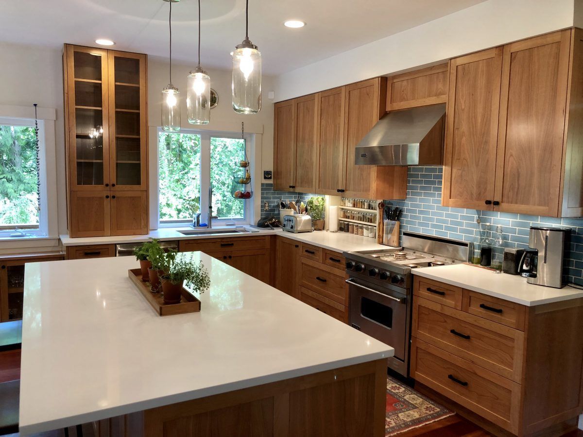 A kitchen with wooden cabinets , stainless steel appliances , and a large island.