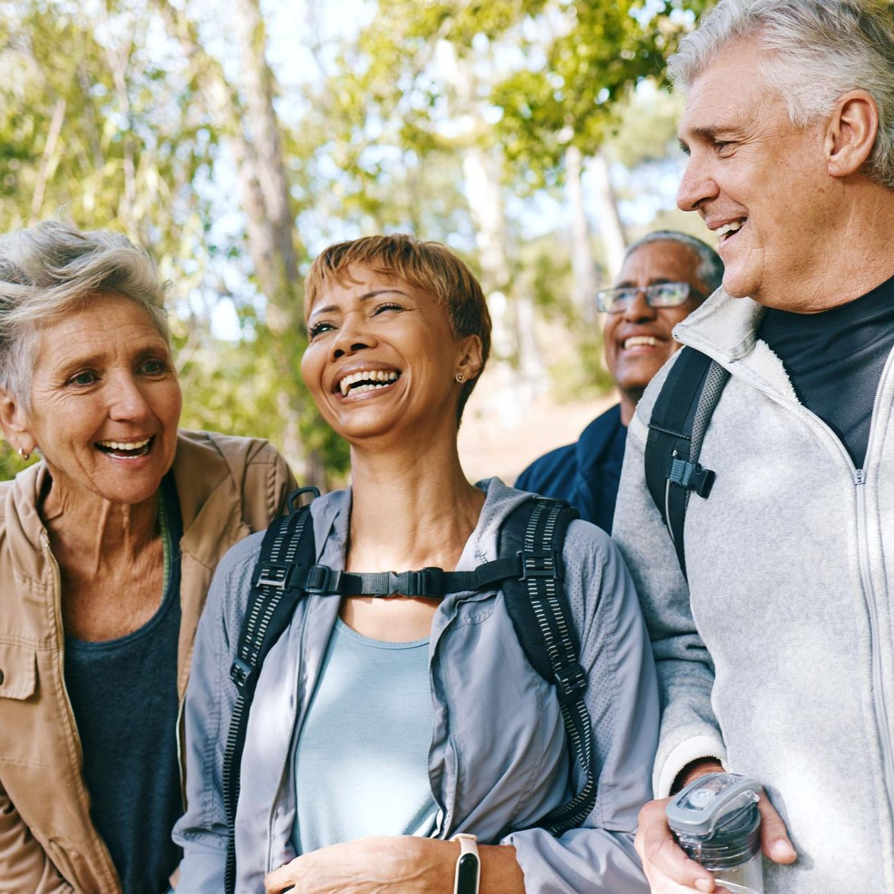 A woman is carrying a little girl on her shoulders in a field at sunset.