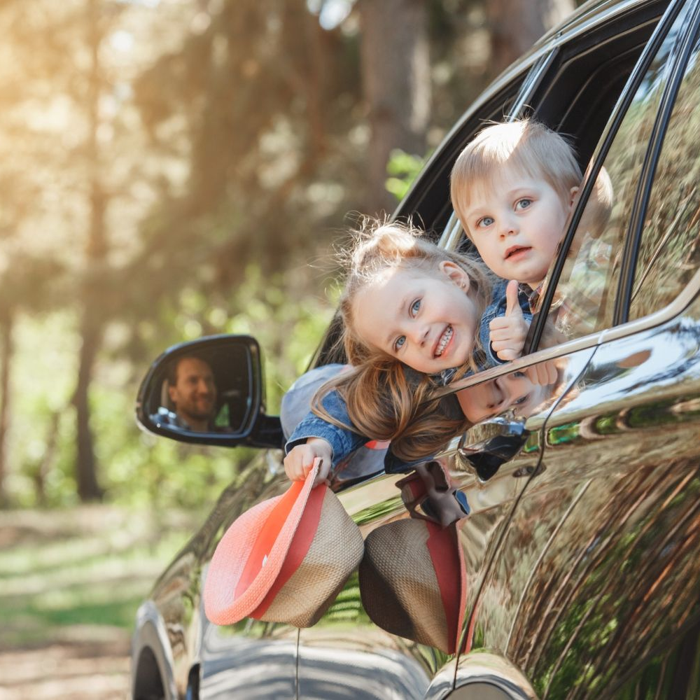 A woman is carrying a little girl on her shoulders in a field at sunset.