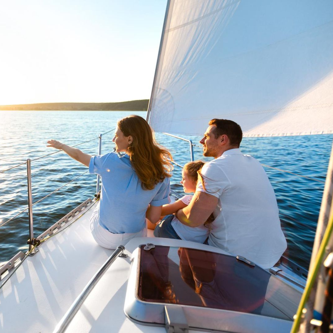 A woman is carrying a little girl on her shoulders in a field at sunset.