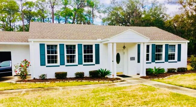 The front door of a house with a porch and plants in front of it.