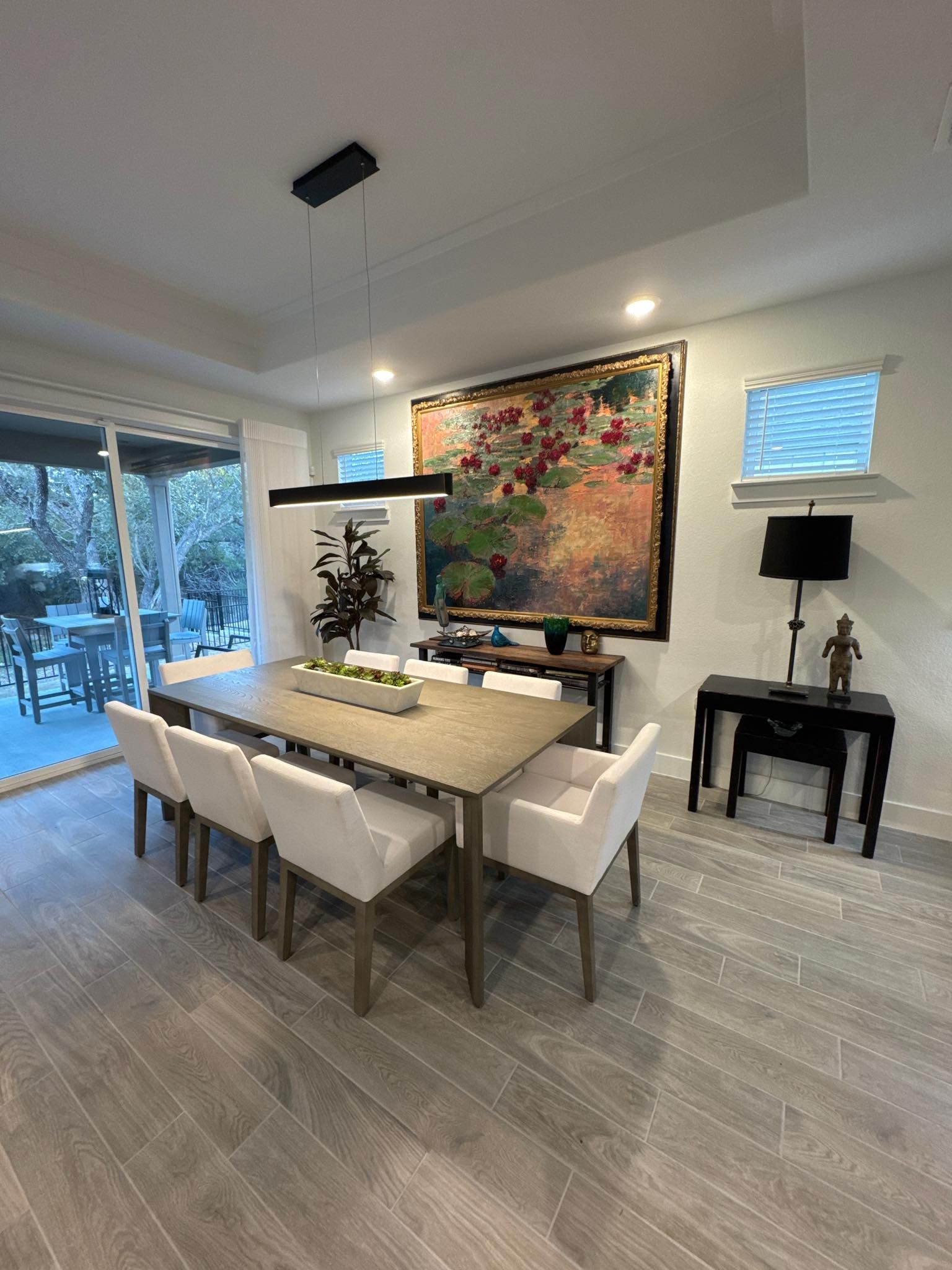 Dining room with large table, white chairs, artwork, and sliding door to patio.