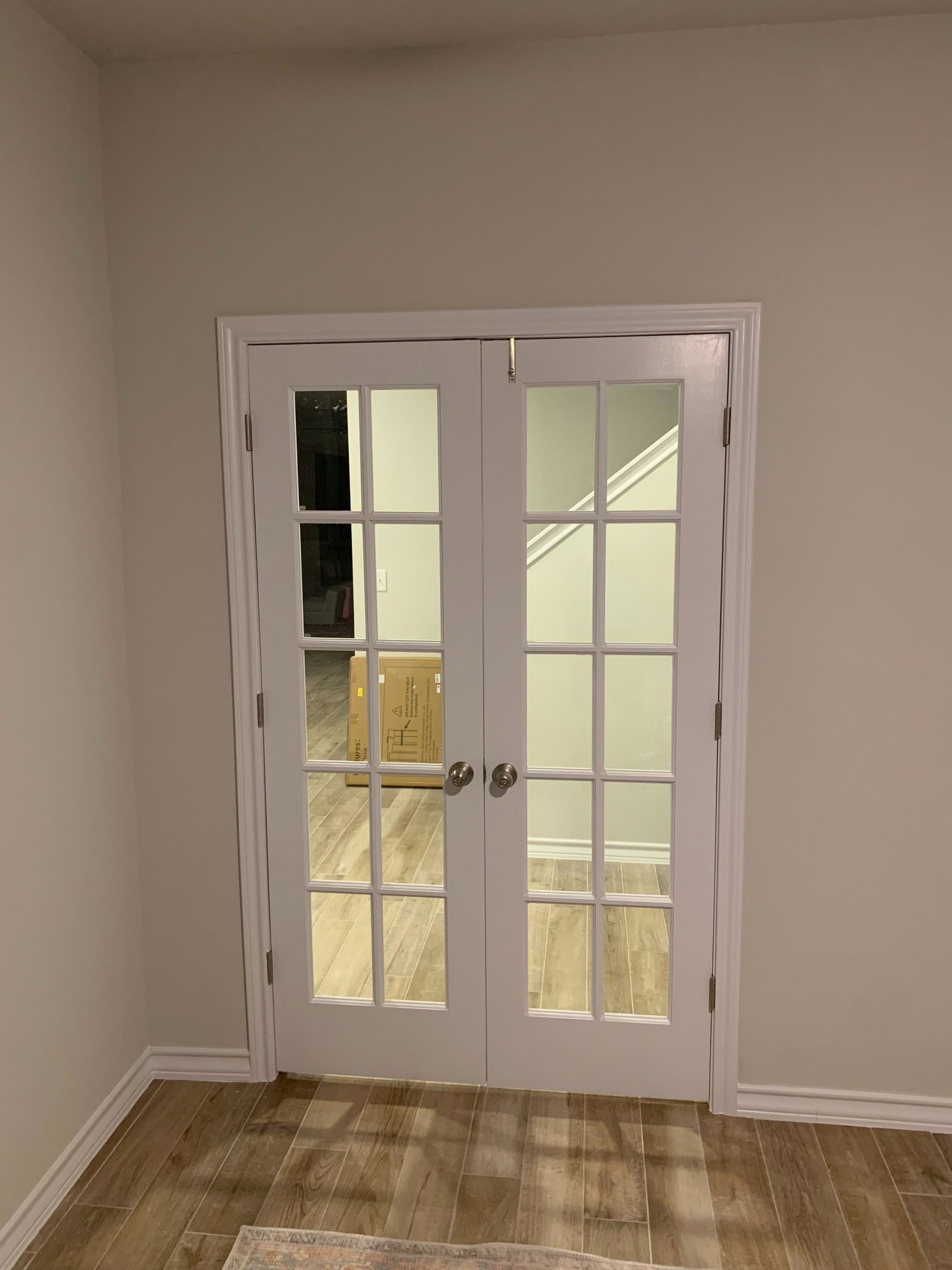 A living room with french doors and a rug on the floor.