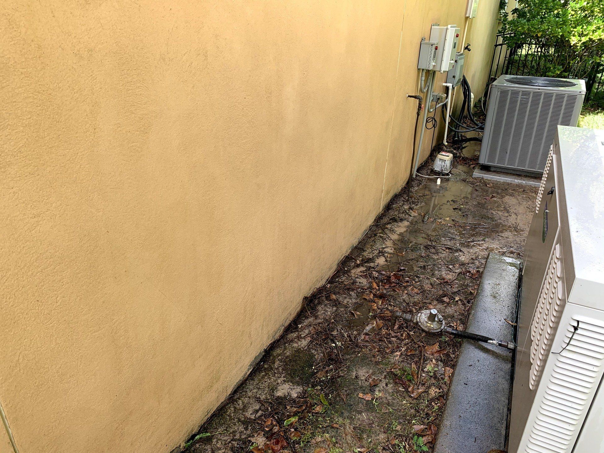 There is a dirty area next to a wall with a air conditioner.