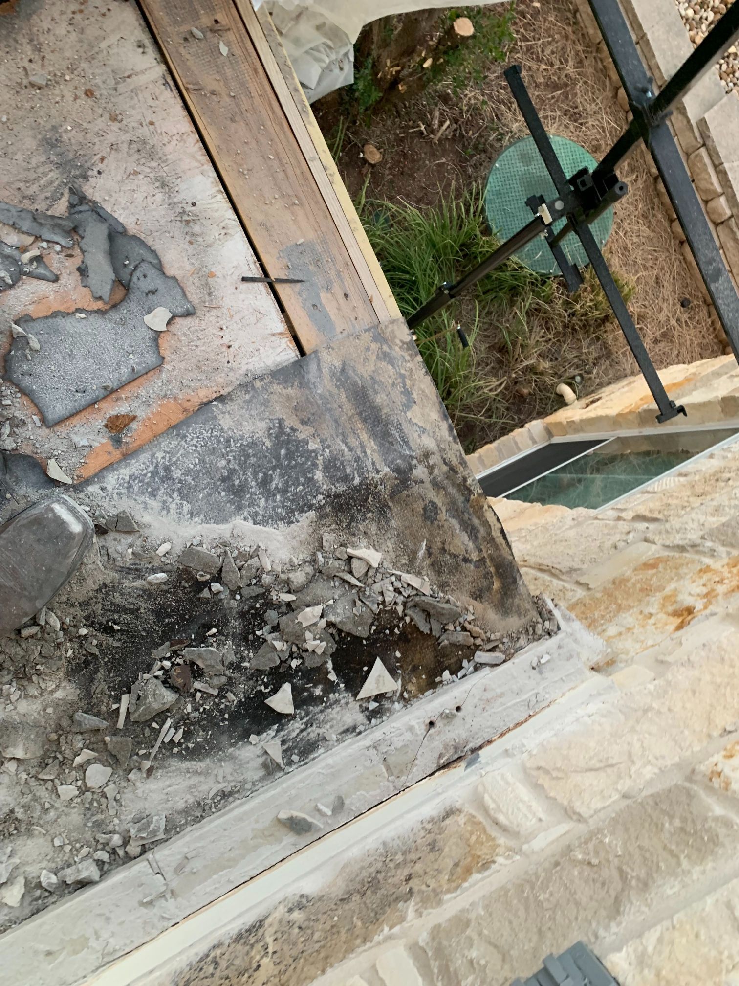 A concrete wall with a hole in it and a pool in the background.
