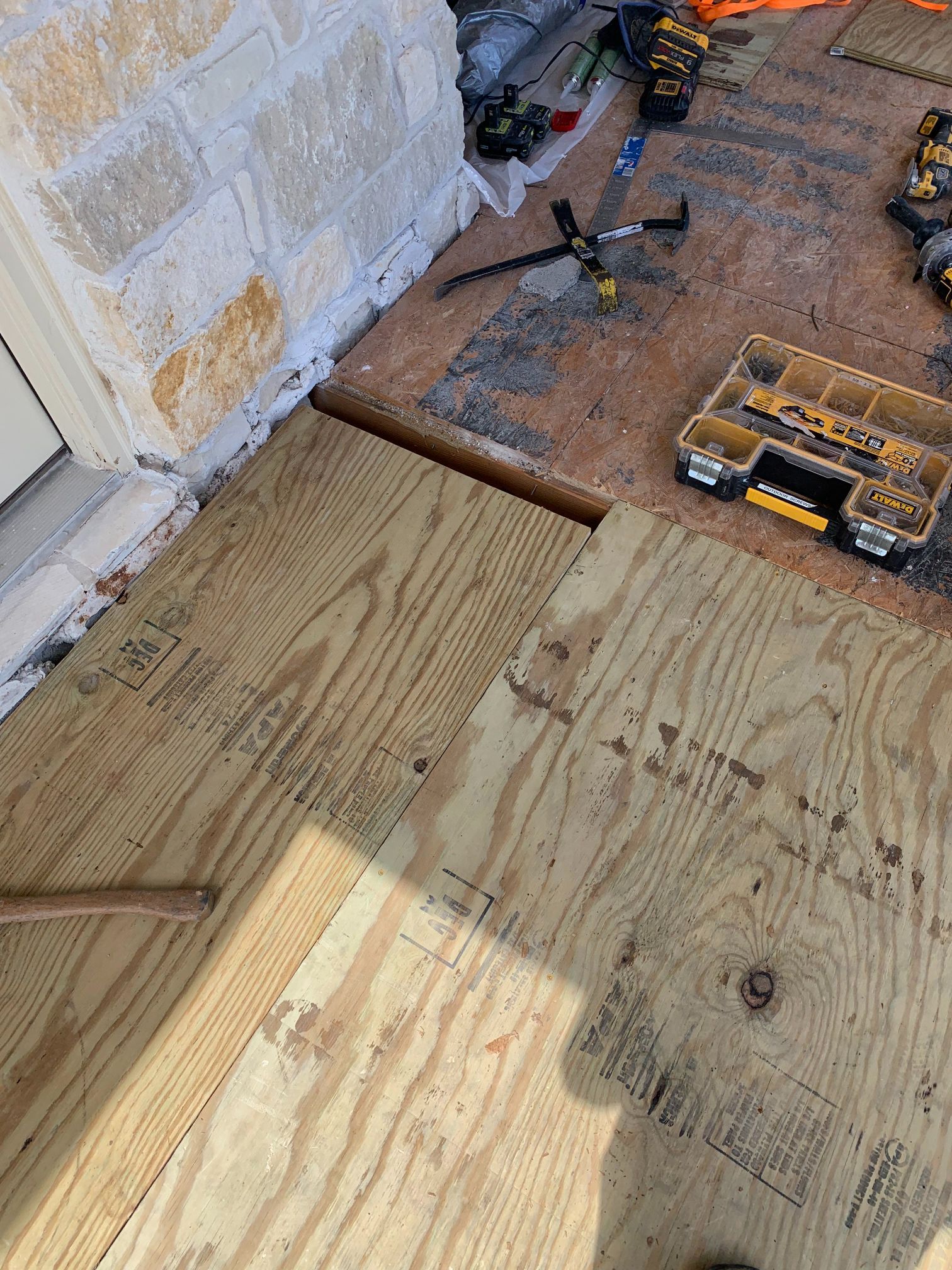 A piece of plywood is sitting on top of a wooden floor next to a toolbox.