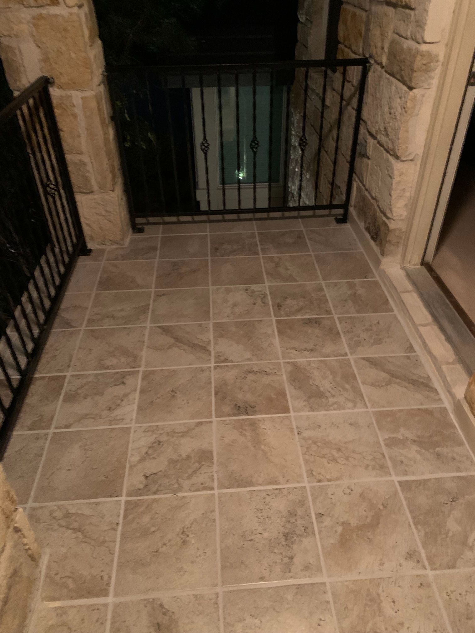 A balcony with tile floors and a metal railing.