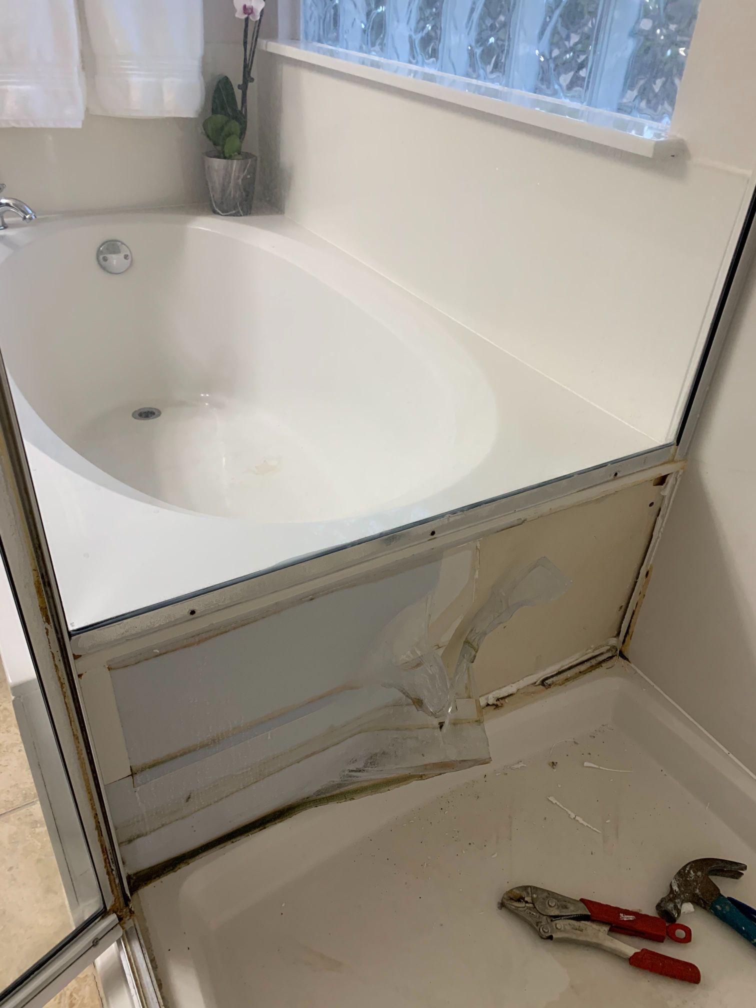 A bathtub is being repaired in a bathroom with tools on the floor.