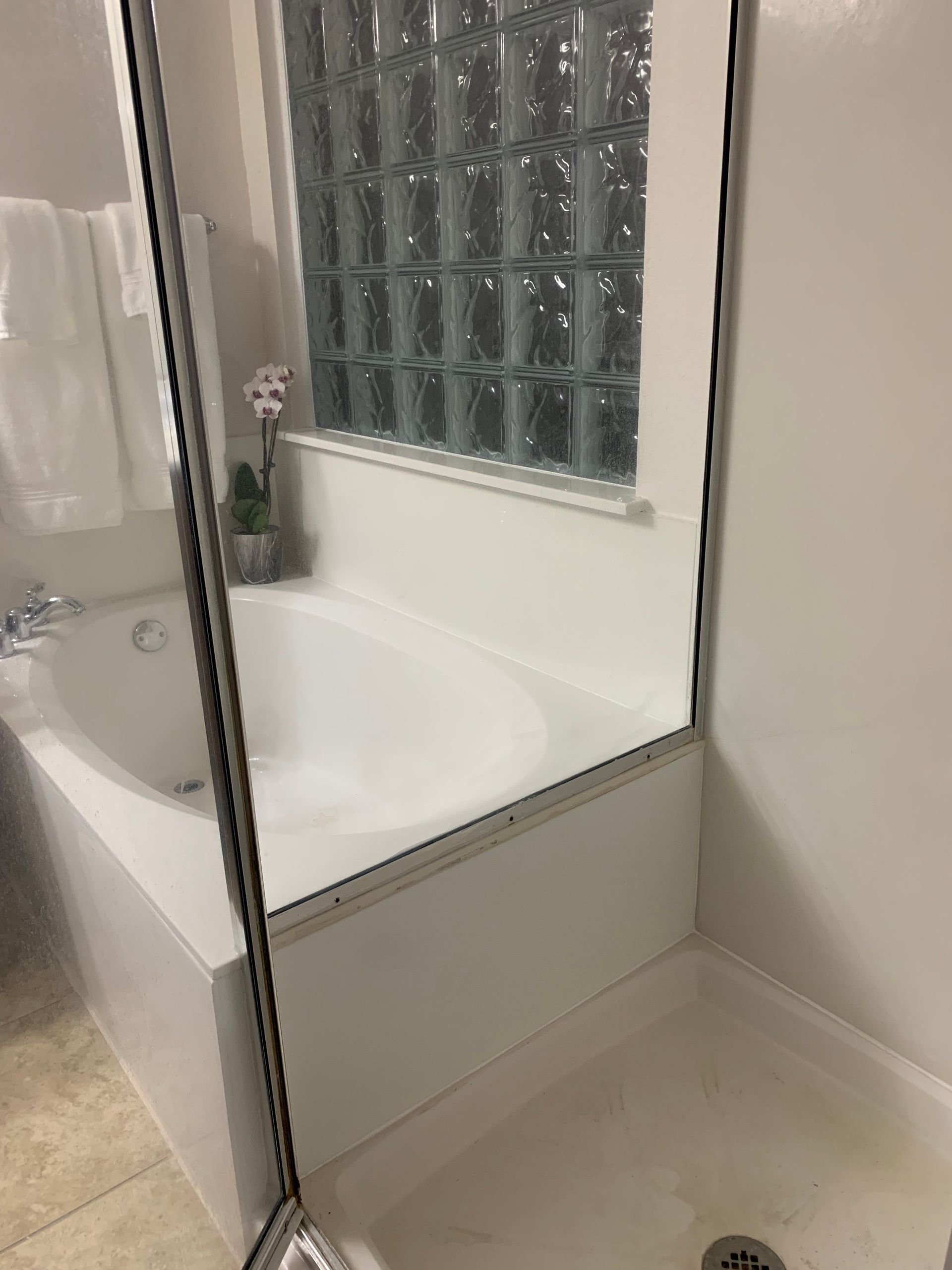 A bathroom with a tub , shower , and mirror.