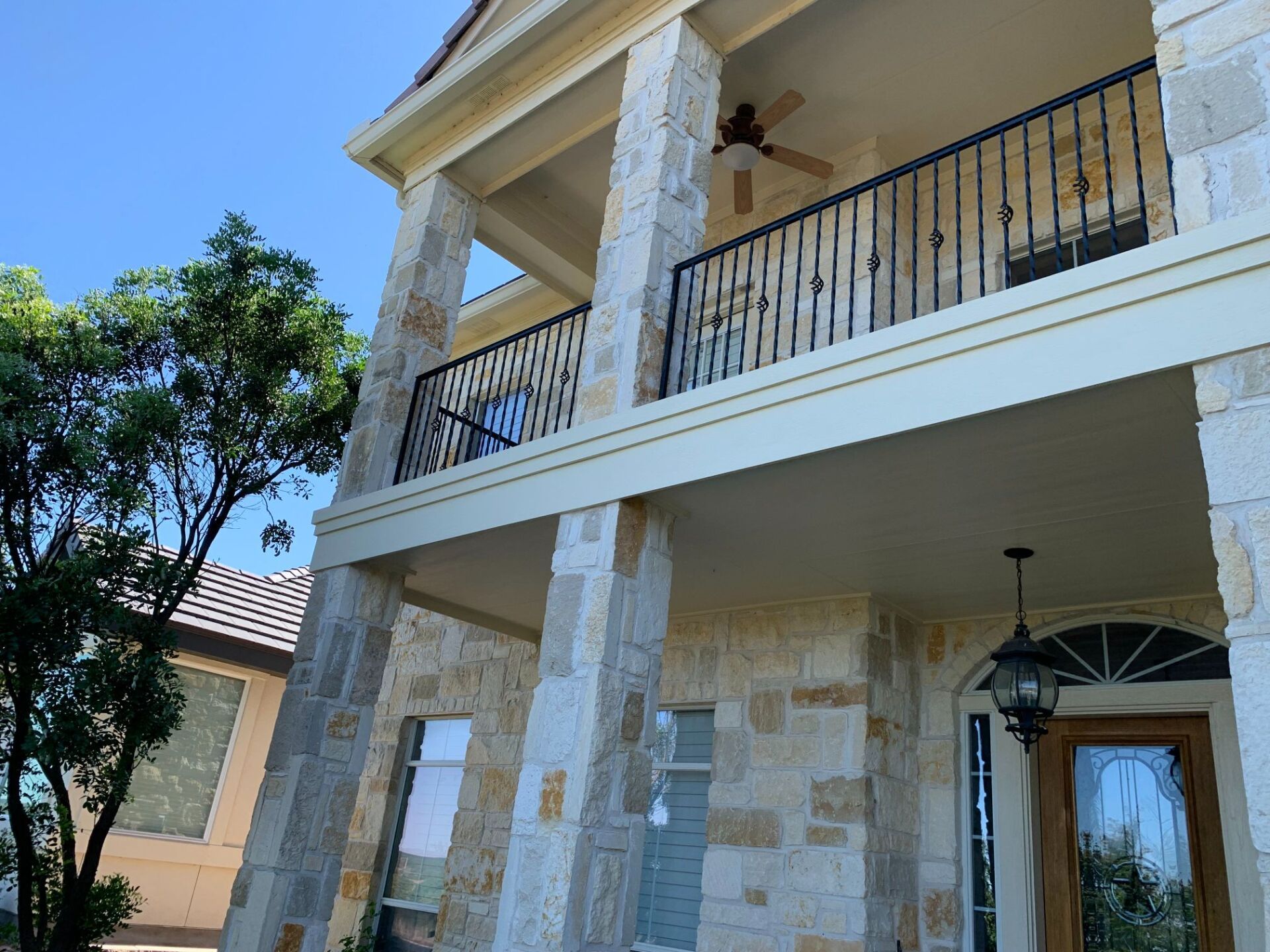 A large stone house with a balcony and a ceiling fan