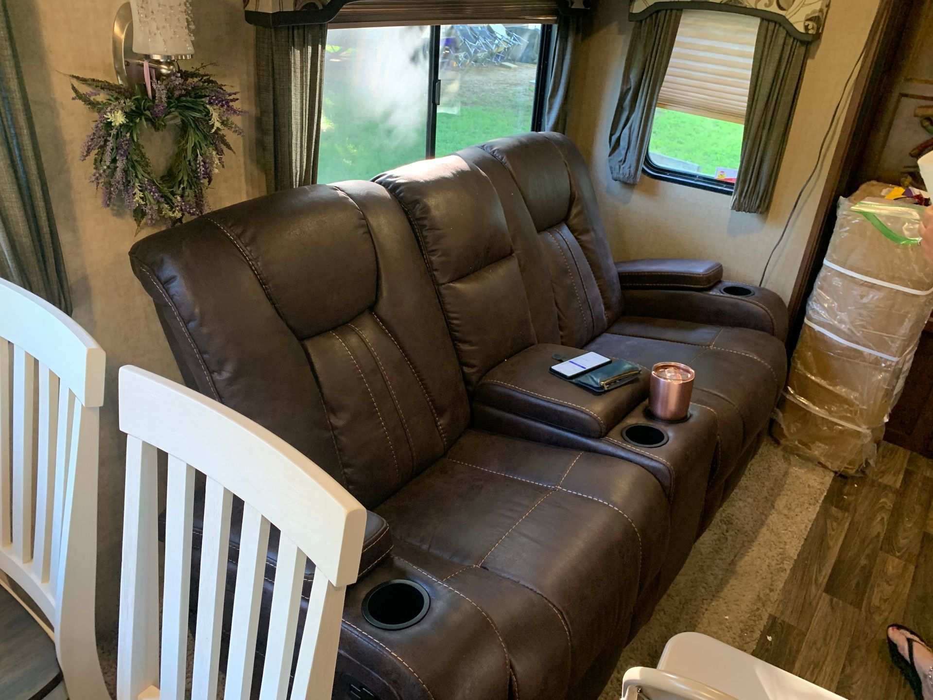 A brown leather couch is sitting in a living room next to a white chair.