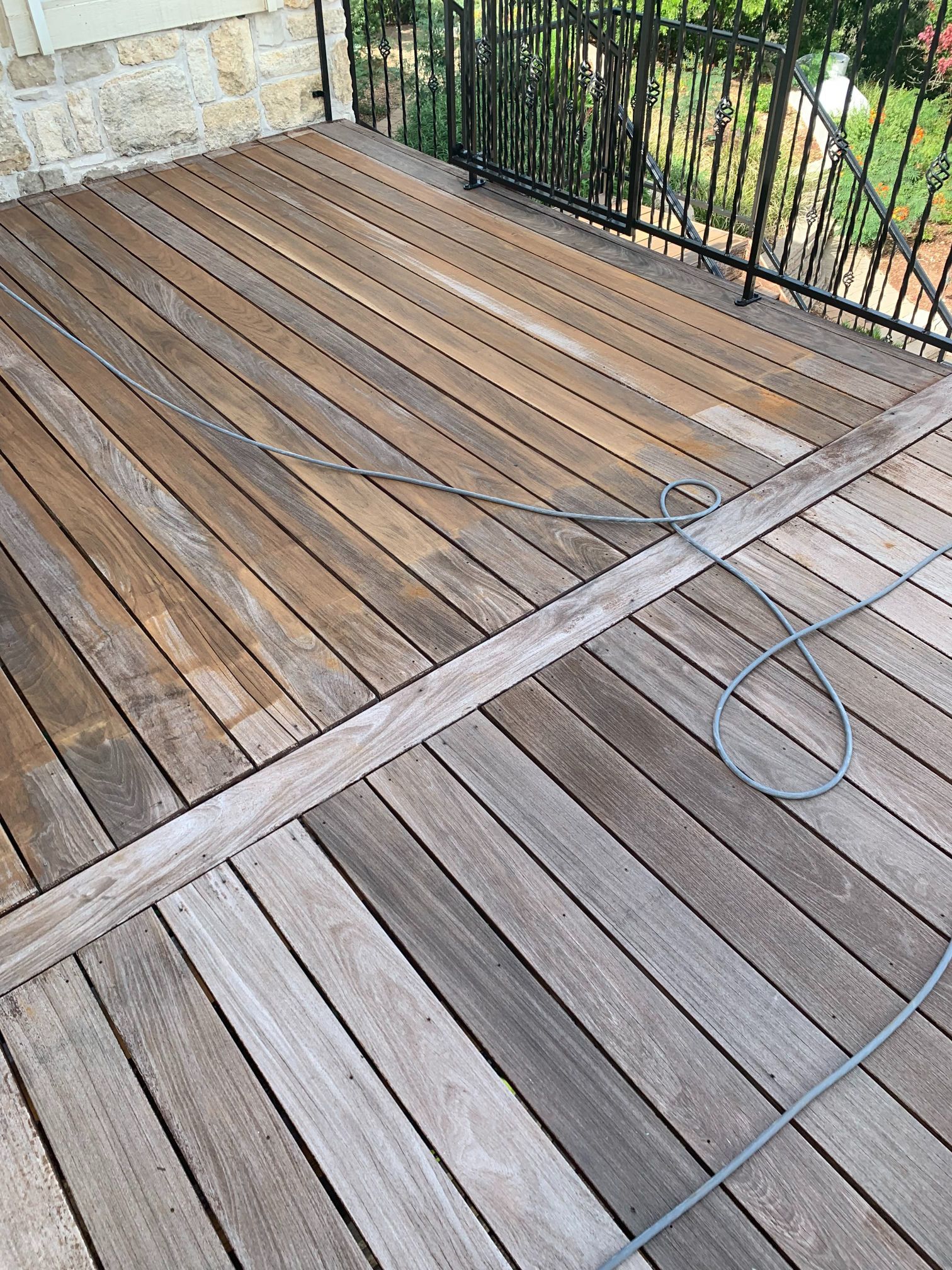 A wooden deck with a wire hanging from it and a fence in the background.
