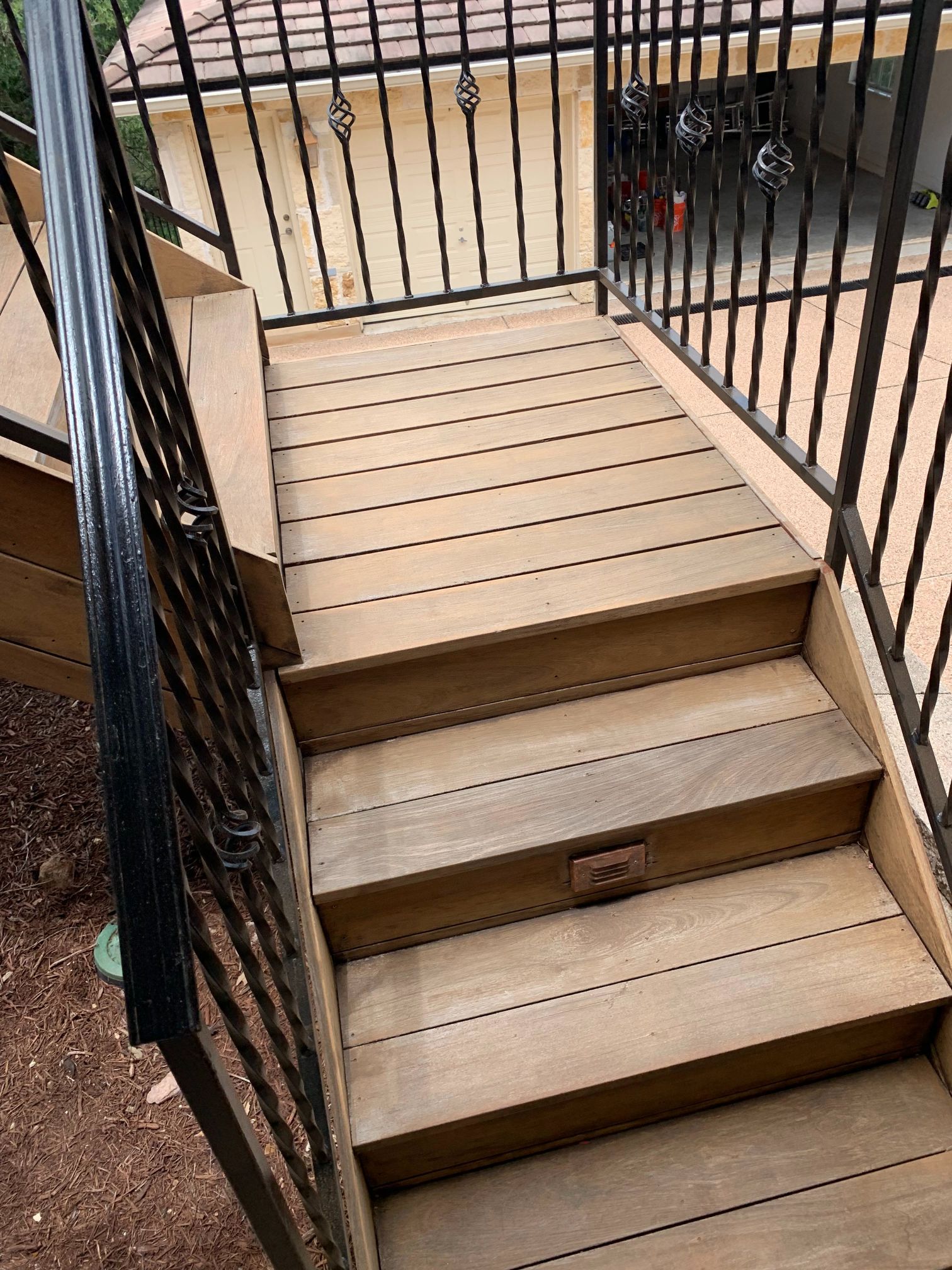 A set of wooden stairs leading up to a deck with a metal railing.