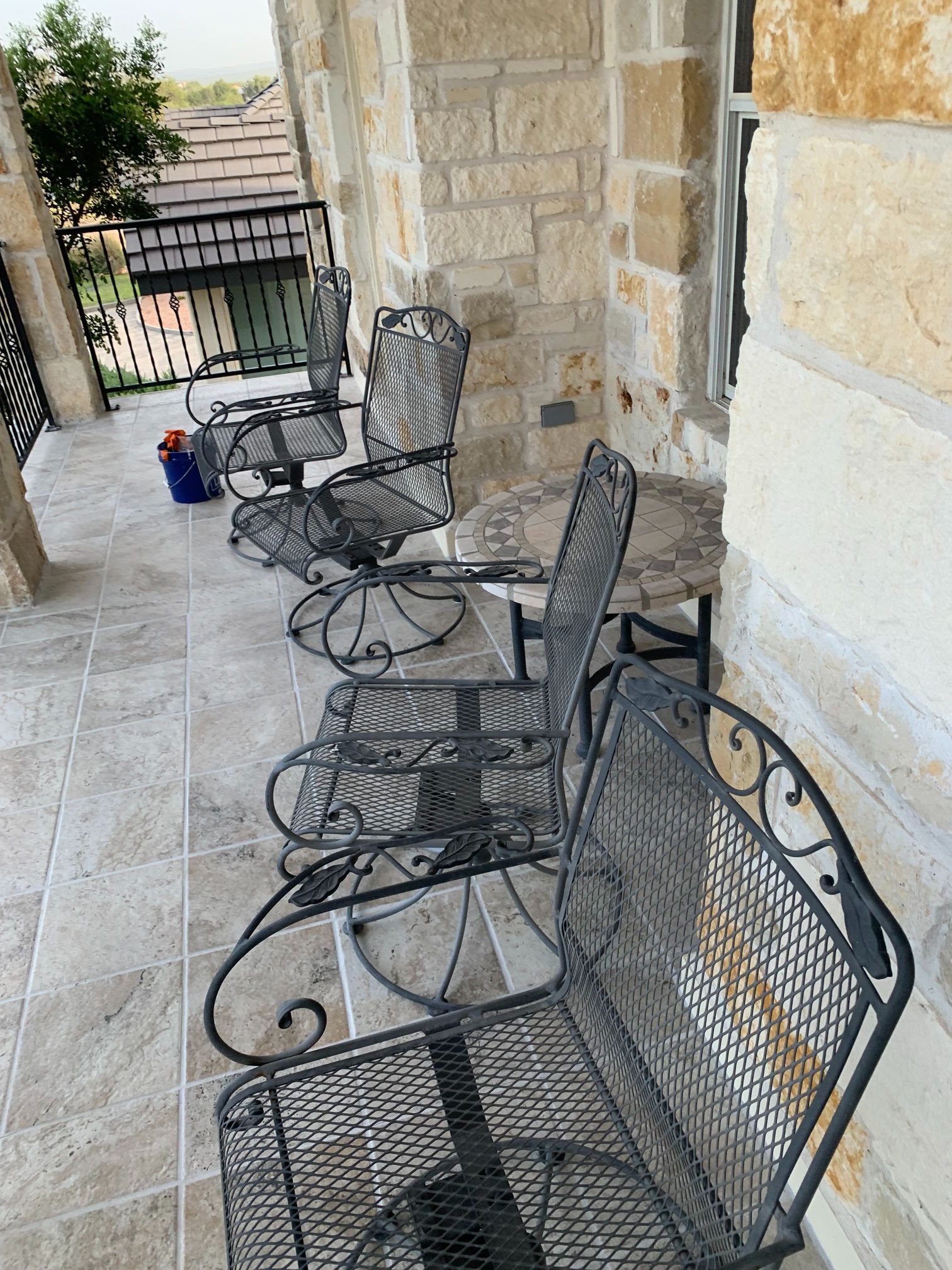 A patio with a bench and chairs on it.