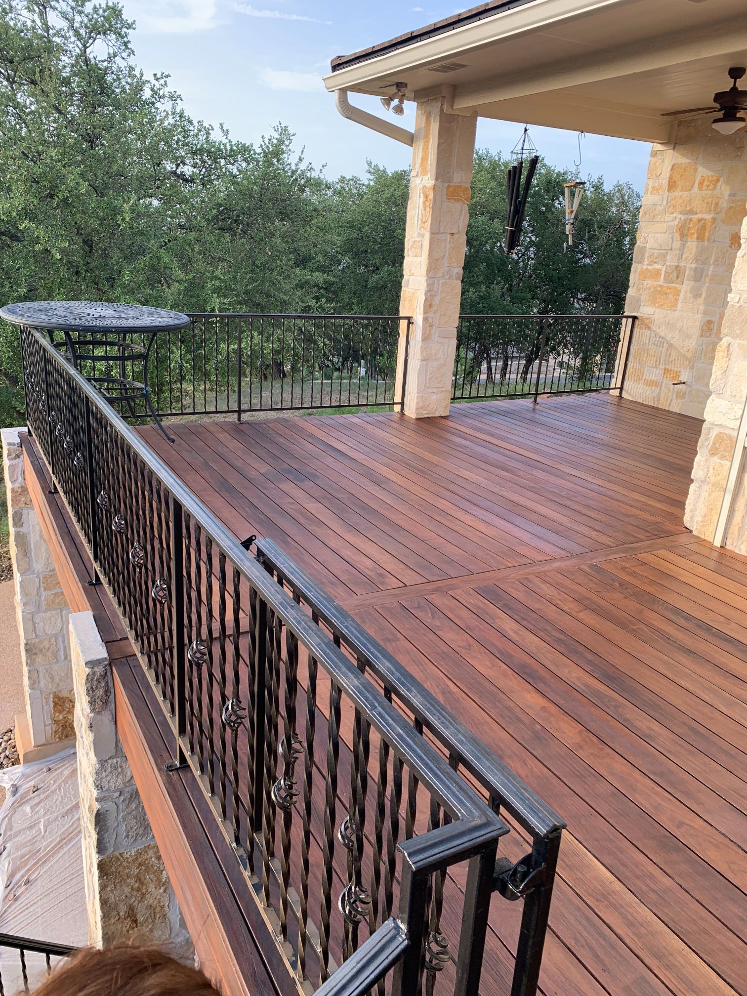 A wooden deck with a wrought iron railing and a table on it.