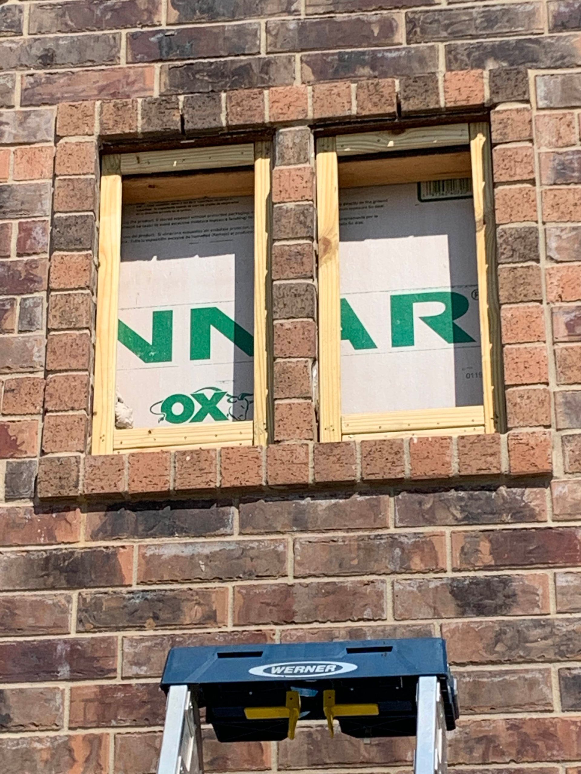 A ladder is sitting on a brick wall next to a window