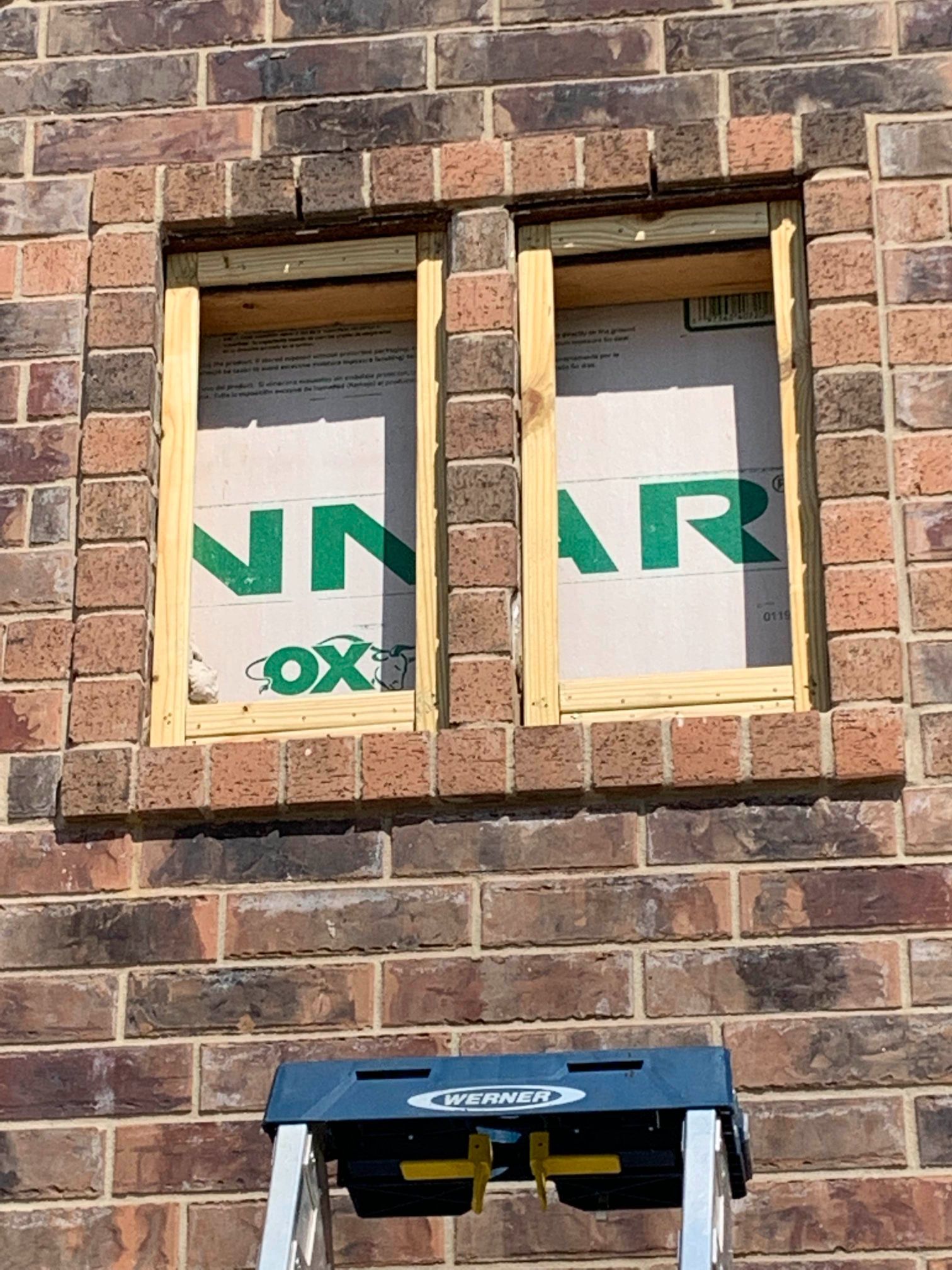 A ladder is sitting on a brick wall next to a window