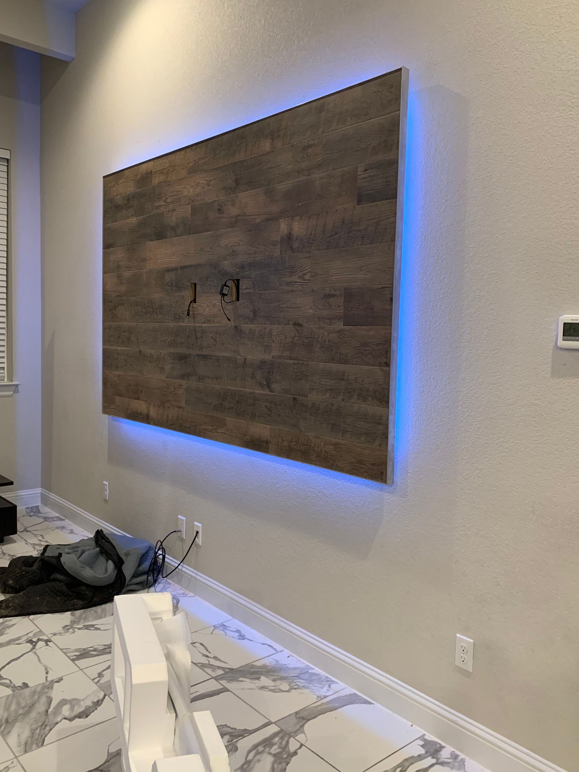 A large wooden wall with blue lights behind it in a living room.