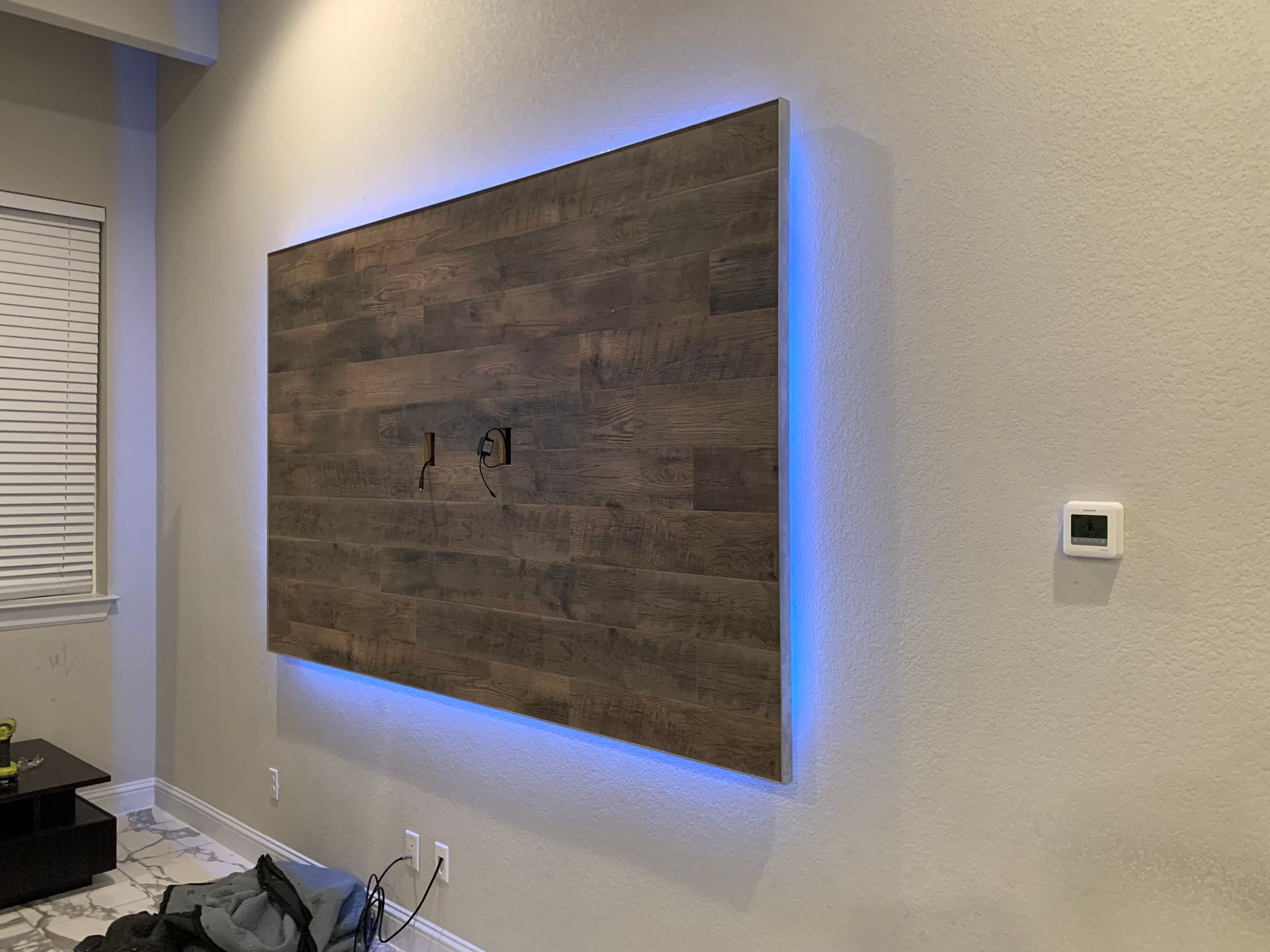 A wooden wall with blue lights behind it in a living room.