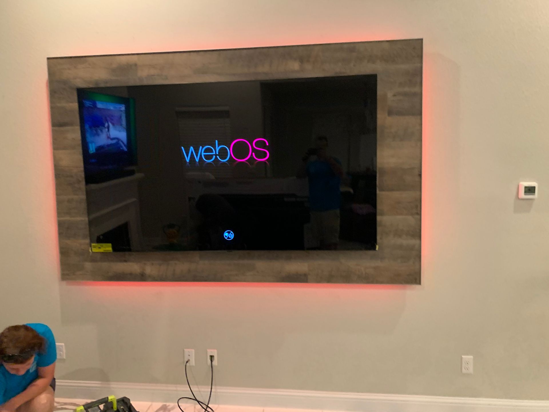 A man is working on a flat screen tv mounted on a wall.