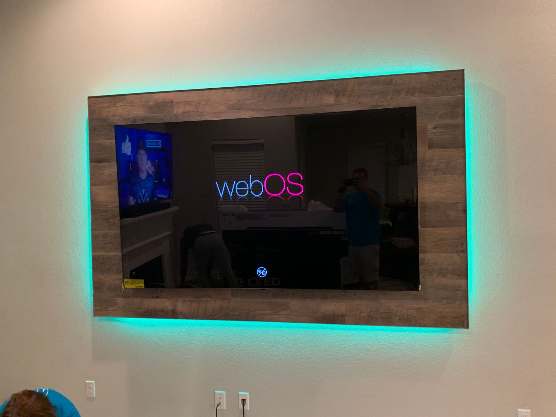 A flat screen tv is hanging on a wall with a wooden frame.